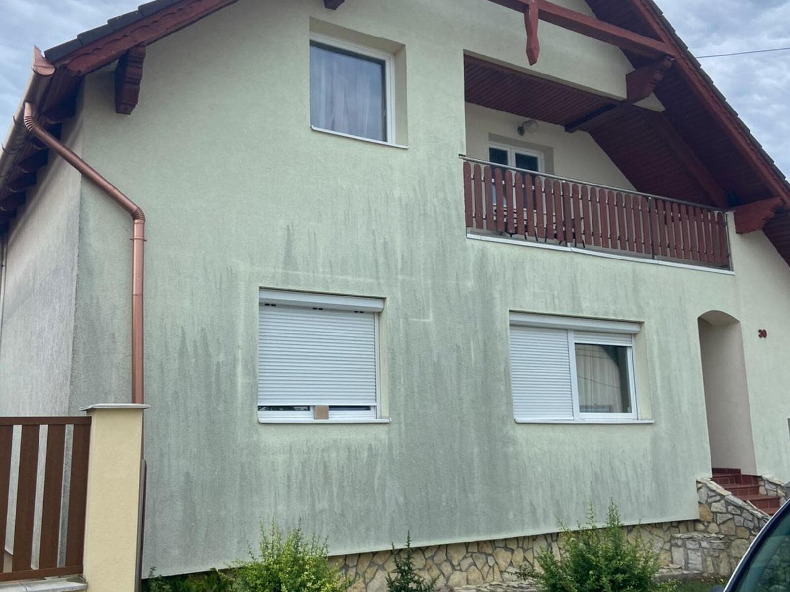 A veresegyházi családi ház kezelt homlokzata, tetőidom és erkély.